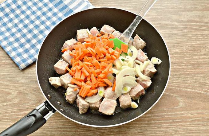Тушкована свинина з цибулею та морквою на сковороді