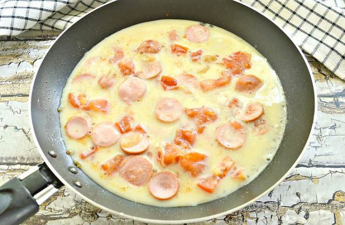 Омлет із сосисками та помідорами на сковороді