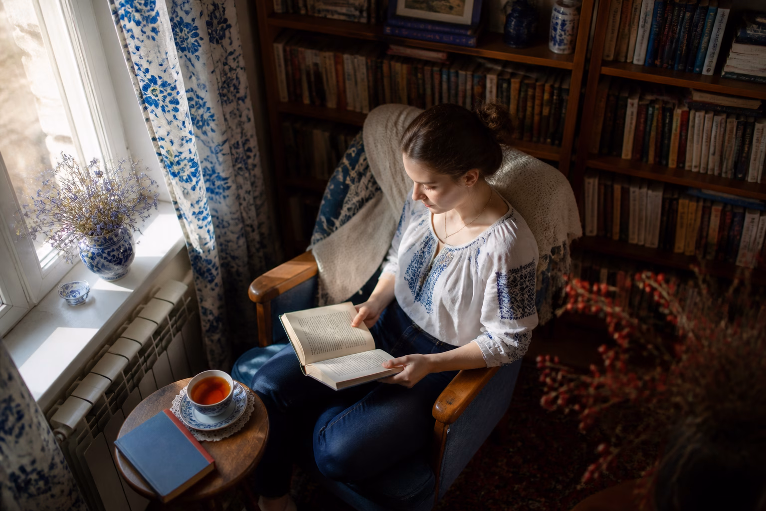 Затишна домашня бібліотека з людиною, яка читає книгу у кріслі