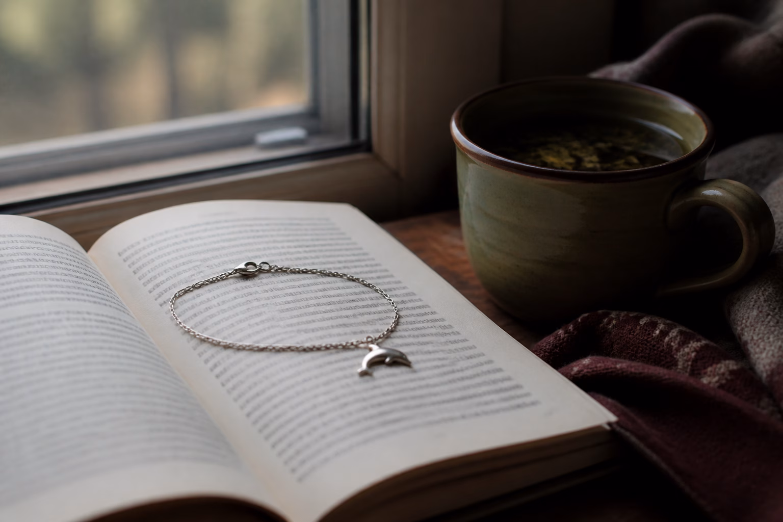 Браслет із підвіскою-дельфіном на розкритій книзі про сновидіння